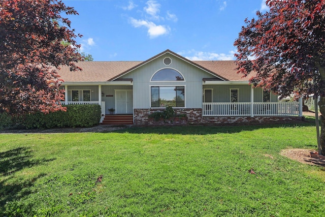 single story home with covered porch, a front yard, a shingled roof, and brick siding