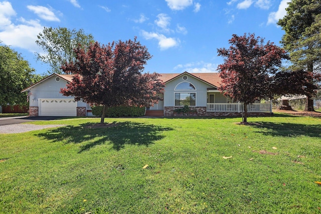 view of front facade featuring gravel driveway, a front lawn, stone siding, and a garage