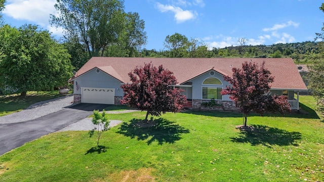 view of front of property featuring stone siding, an attached garage, driveway, and a front lawn