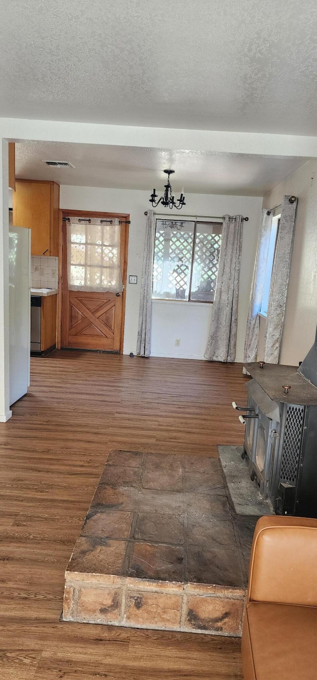 7670 Cedar Crest Rd, Shingletown, CA 96088 - entrance foyer with wood finished floors, a wood stove, a textured ceiling, and healthy amount of natural light
