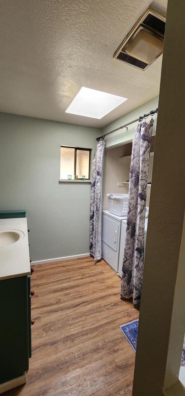 7670 Cedar Crest Rd, Shingletown, CA 96088 - full bathroom with washer and dryer, vanity, wood finished floors, a textured ceiling, and baseboards