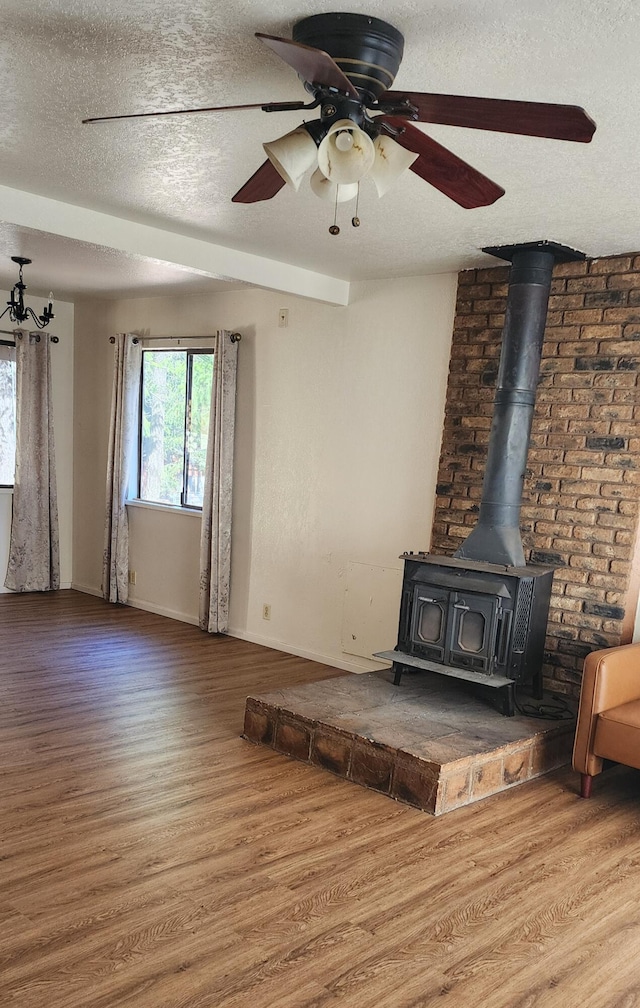 7670 Cedar Crest Rd, Shingletown, CA 96088 - unfurnished living room featuring a wood stove, a textured ceiling, wood finished floors, baseboards, and ceiling fan