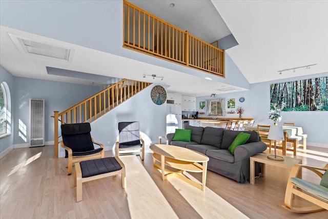 12876 E Fork Rd, French Gulch, CA 96033 - living room with a heating unit, rail lighting, light wood-style flooring, high vaulted ceiling, and stairway