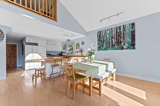 12876 E Fork Rd, French Gulch, CA 96033 - dining space featuring rail lighting, light wood-type flooring, baseboards, and high vaulted ceiling