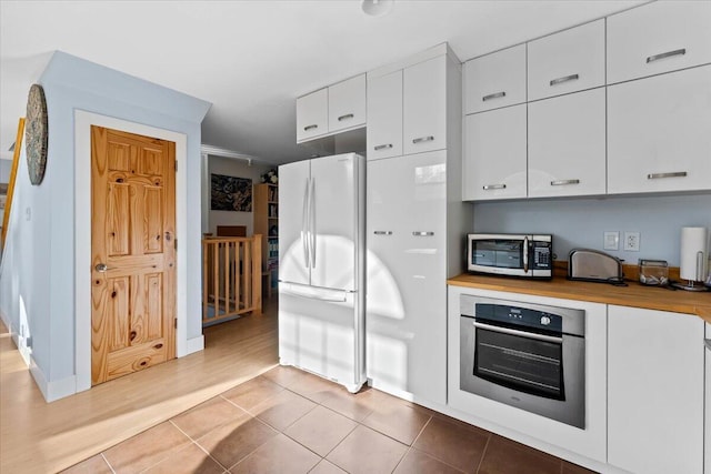 12876 E Fork Rd, French Gulch, CA 96033 - kitchen with appliances with stainless steel finishes, white cabinets, butcher block countertops, tile patterned floors, and baseboards