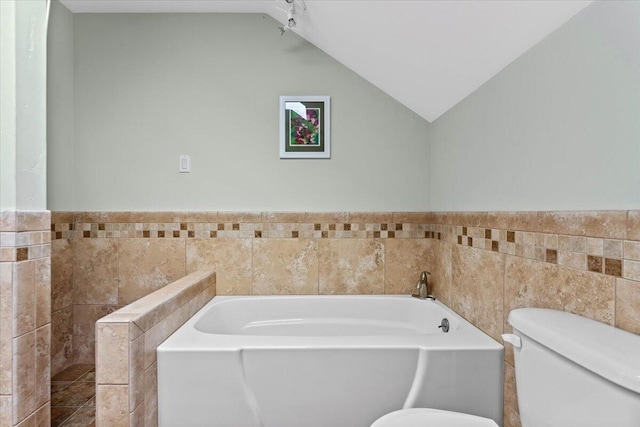 12876 E Fork Rd, French Gulch, CA 96033 - full bathroom featuring toilet, tile walls, a garden tub, lofted ceiling, and wainscoting