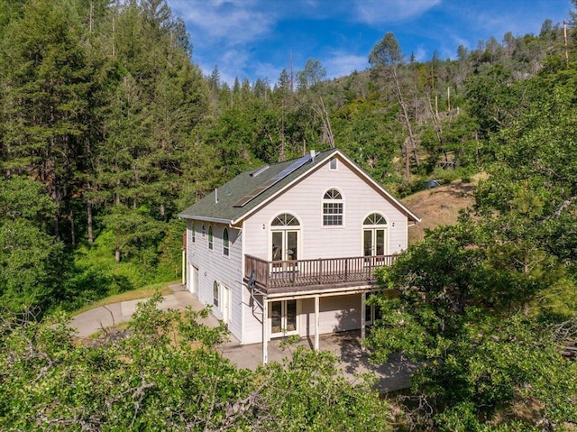 12876 E Fork Rd, French Gulch, CA 96033 - back of house with a wooded view, a wooden deck, french doors, driveway, and solar panels