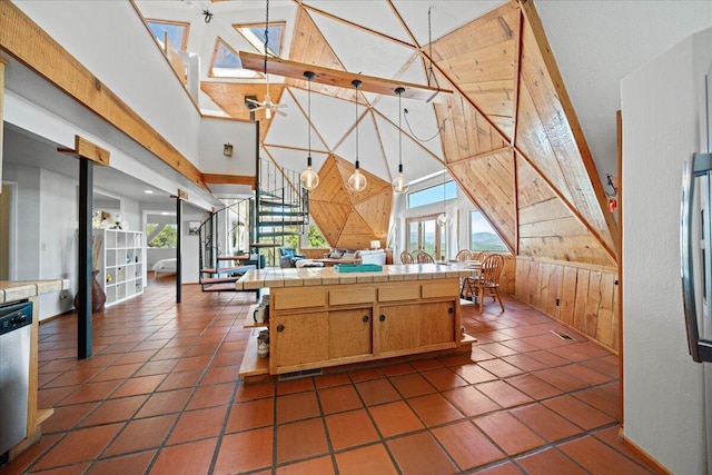 19028 Rocky Trl, Lakehead, CA 96051 - kitchen featuring tile countertops, wood walls, plenty of natural light, a towering ceiling, and stainless steel dishwasher