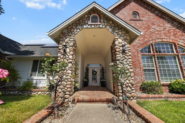 2154 Harvard Way, Redding, CA 96003 - doorway to property featuring solar panels, brick siding, roof with shingles, and a yard