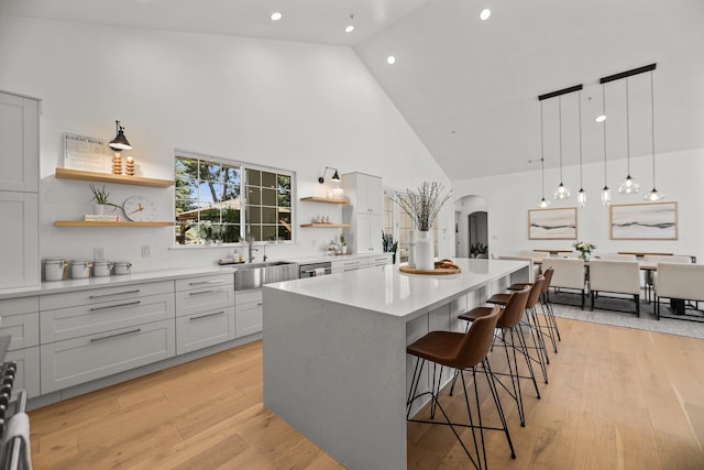 2154 Harvard Way, Redding, CA 96003 - kitchen featuring high vaulted ceiling, open shelves, arched walkways, a center island, and a sink