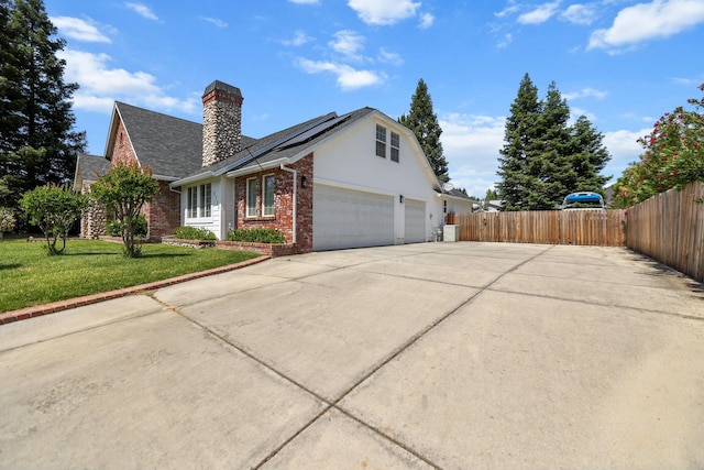 2154 Harvard Way, Redding, CA 96003 - view of front of home featuring brick siding, driveway, a chimney, roof mounted solar panels, and a garage
