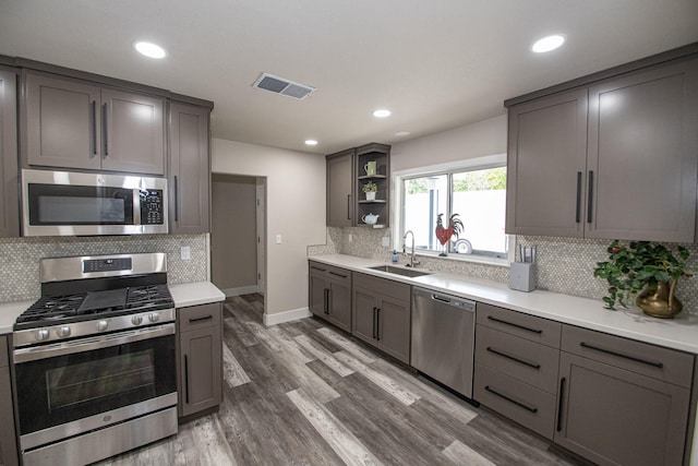 75 Sherman Dr, Red Bluff, CA 96080 - kitchen with appliances with stainless steel finishes, a sink, open shelves, wood finished floors, and decorative backsplash