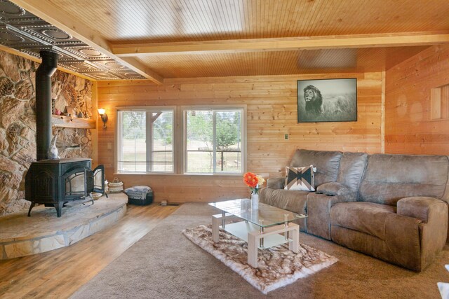27339 Hobart Rd, Shingletown, CA 96088 - living room featuring a wood stove, beam ceiling, wood walls, wood finished floors, and wooden ceiling
