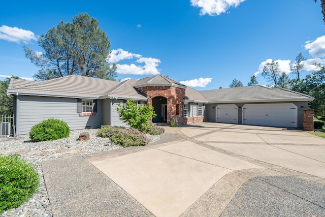 view of front of house with concrete driveway, an attached garage, cooling unit, and a tiled roof