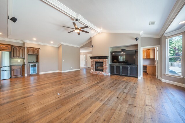 unfurnished living room with a ceiling fan, light wood finished floors, baseboards, a fireplace, and ornamental molding