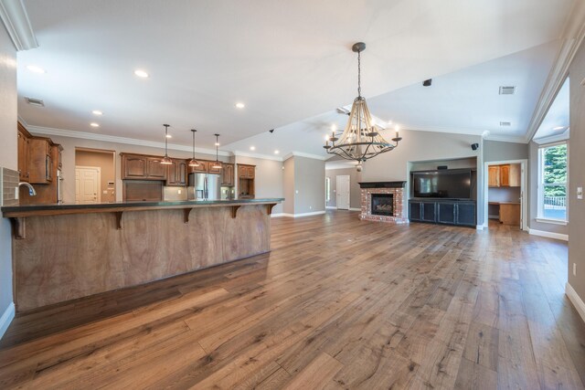 kitchen featuring stainless steel fridge with ice dispenser, baseboards, open floor plan, a kitchen bar, and wood finished floors