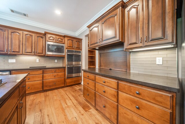 kitchen with stainless steel appliances, decorative backsplash, light wood finished floors, crown molding, and brown cabinets