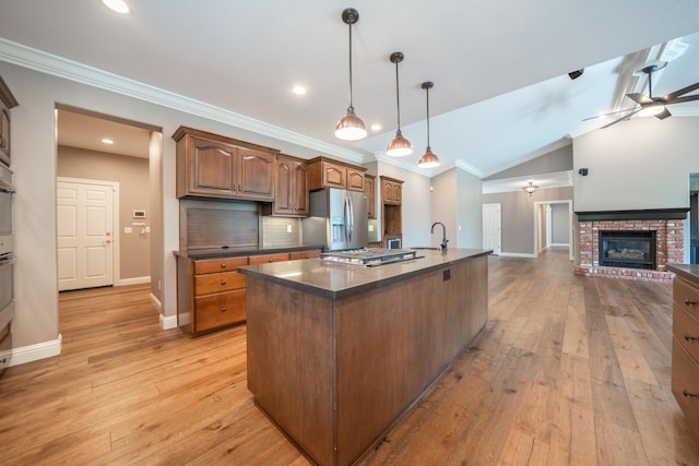 kitchen featuring stainless steel appliances, dark countertops, ceiling fan, a sink, and ornamental molding
