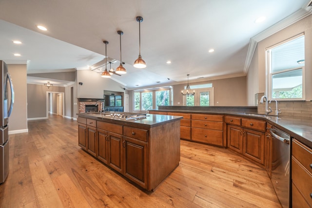 kitchen with ornamental molding, a sink, stainless steel appliances, brown cabinets, and open floor plan
