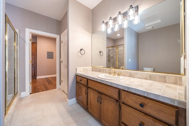 bathroom with a stall shower, baseboards, tile patterned floors, and vanity
