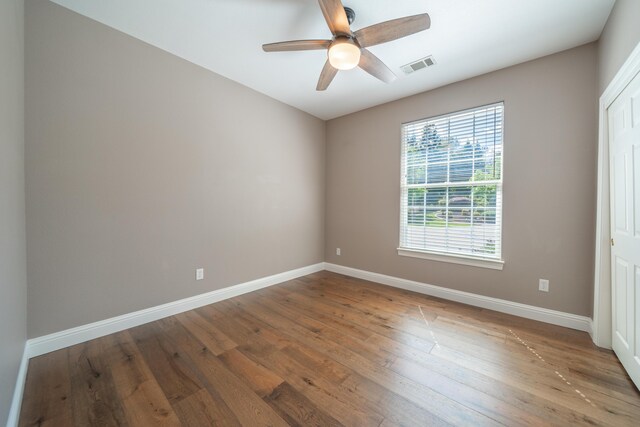 spare room featuring ceiling fan, hardwood / wood-style flooring, and baseboards