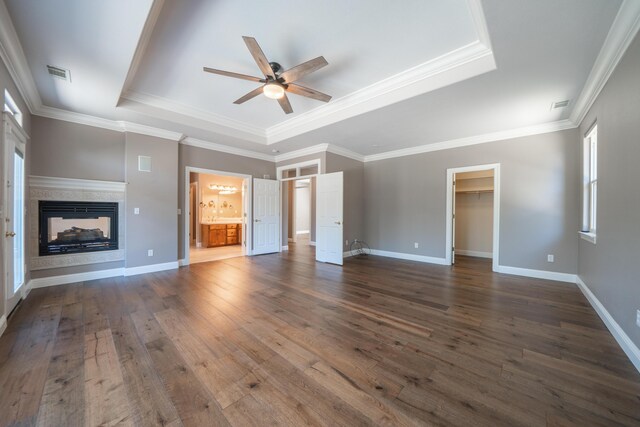 unfurnished living room featuring a raised ceiling, a ceiling fan, dark wood-style floors, a multi sided fireplace, and crown molding