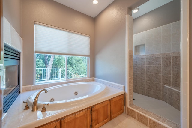 bathroom with a walk in shower, a jetted tub, and tile patterned flooring