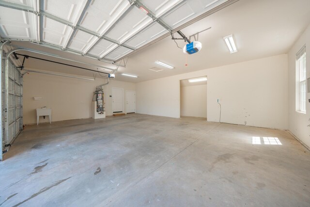 garage with a garage door opener, strapped water heater, and a sink