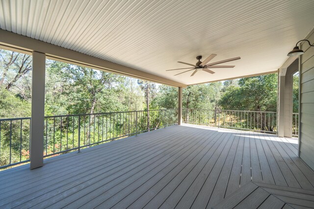 wooden terrace with a ceiling fan and view of wooded area