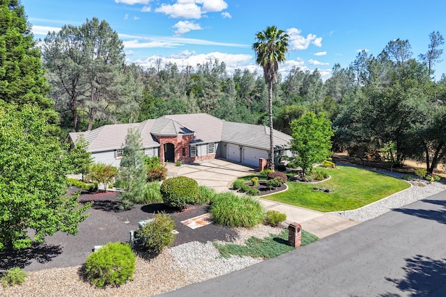 view of front facade featuring an attached garage, a tile roof, concrete driveway, and a front yard
