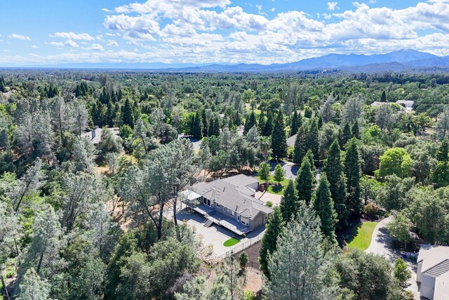 aerial view of property and surrounding area with a forest and a mountainous background
