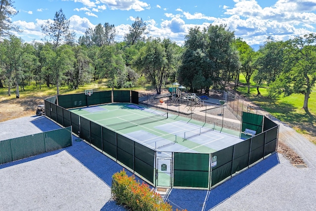 view of tennis court featuring fence and view of wooded area
