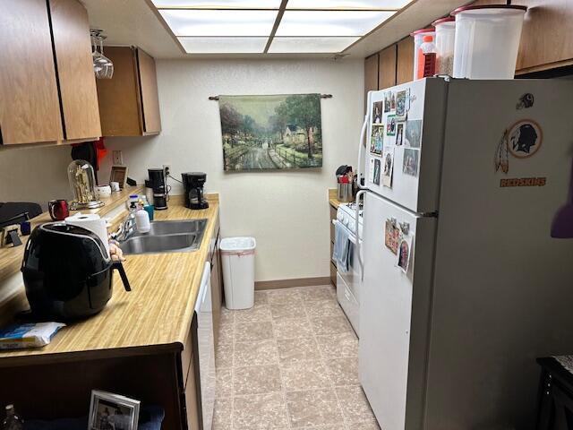3580 Ricardo Ave, Redding, CA 96002 - kitchen with white appliances, a sink, light countertops, baseboards, and an office area