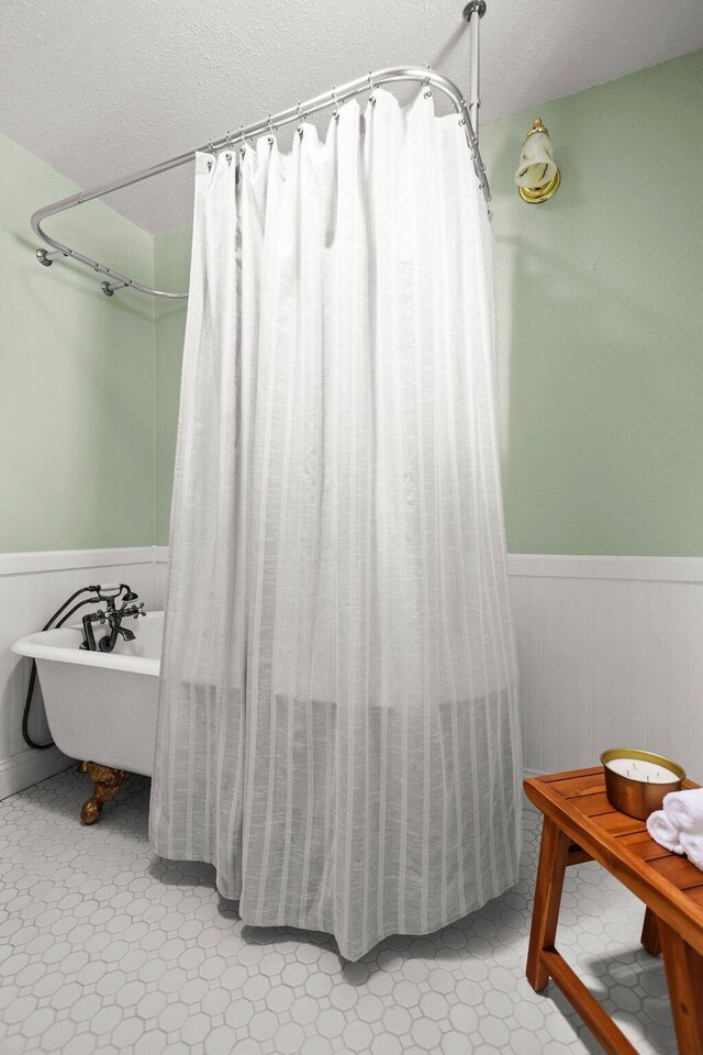 19186 Knighton Rd, Redding, CA 96001 - full bath featuring wainscoting, a soaking tub, a textured ceiling, and a shower with curtain