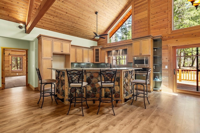 7185 Whispering Winds Ct, Shingletown, CA 96088 - kitchen with stainless steel microwave, high vaulted ceiling, healthy amount of natural light, light wood finished floors, and wooden ceiling with exposed beams