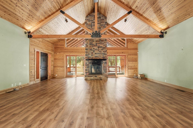 7185 Whispering Winds Ct, Shingletown, CA 96088 - unfurnished living room featuring wood finished floors, high vaulted ceiling, wooden walls, a stone fireplace, and baseboards