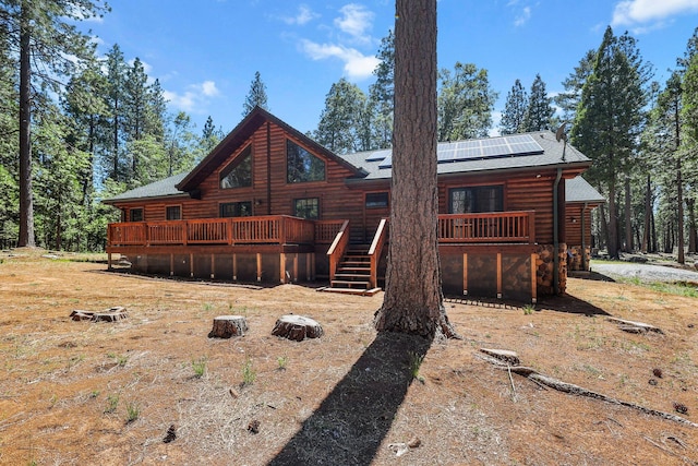 7185 Whispering Winds Ct, Shingletown, CA 96088 - back of property with a wooden deck, solar panels, and roof with shingles