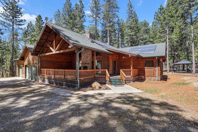 7185 Whispering Winds Ct, Shingletown, CA 96088 - view of front of house featuring driveway, a gazebo, solar panels, a chimney, and an attached garage