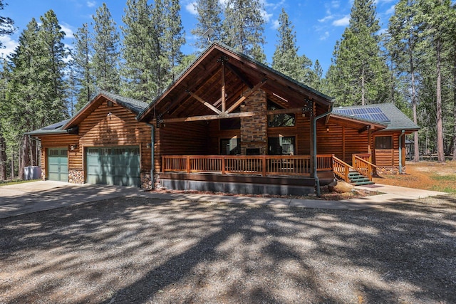7185 Whispering Winds Ct, Shingletown, CA 96088 - view of front facade featuring a garage, driveway, solar panels, faux log siding, and a porch