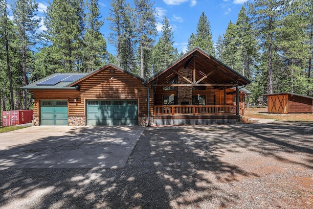 7185 Whispering Winds Ct, Shingletown, CA 96088 - view of front facade featuring a porch, a garage, driveway, roof mounted solar panels, and stone siding