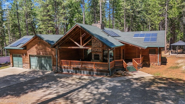 7185 Whispering Winds Ct, Shingletown, CA 96088 - view of front of property featuring asphalt driveway, covered porch, roof mounted solar panels, an attached garage, and a chimney