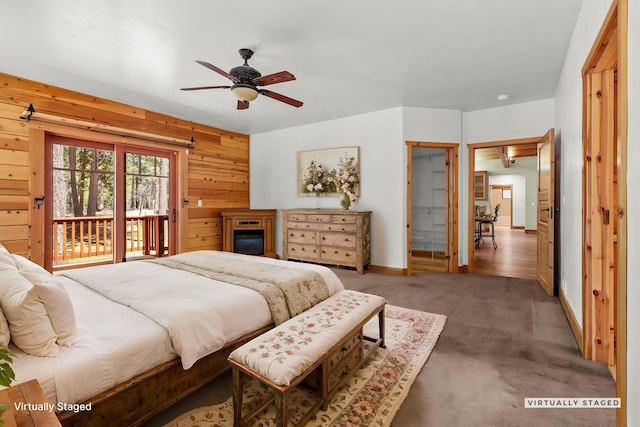 7185 Whispering Winds Ct, Shingletown, CA 96088 - bedroom with access to exterior, baseboards, a fireplace, carpet floors, and wood walls