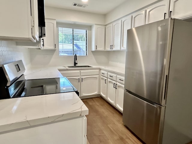 1808 Del Mar Ave, Redding, CA 96003 - kitchen featuring freestanding refrigerator, a sink, white cabinets, light wood-type flooring, and range with electric stovetop