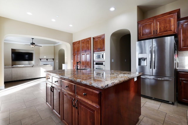 20284 Domaine Pl, Anderson, CA 96007 - kitchen featuring appliances with stainless steel finishes, arched walkways, a ceiling fan, a sink, and a center island with sink