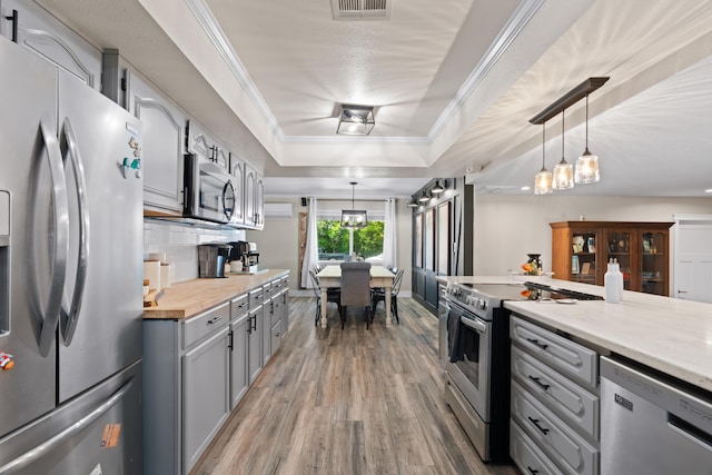 3689 Suzanne Way, Redding, CA 96002 - kitchen with appliances with stainless steel finishes, gray cabinetry, a raised ceiling, wood finished floors, and hanging light fixtures