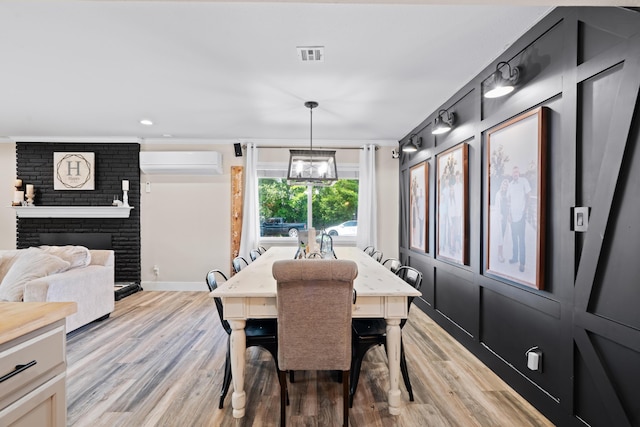 3689 Suzanne Way, Redding, CA 96002 - dining room featuring a wall mounted air conditioner, light wood-type flooring, a brick fireplace, crown molding, and baseboards