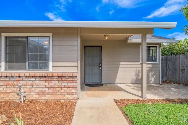 property entrance with fence and brick siding