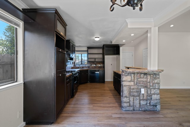 kitchen with black appliances, light wood finished floors, crown molding, dark stone countertops, and baseboards