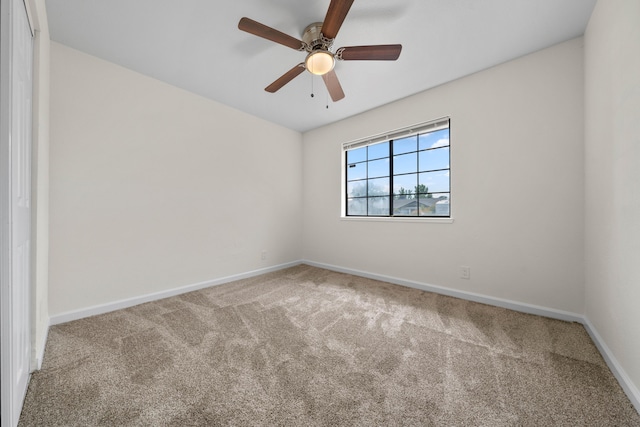 carpeted spare room with baseboards and a ceiling fan