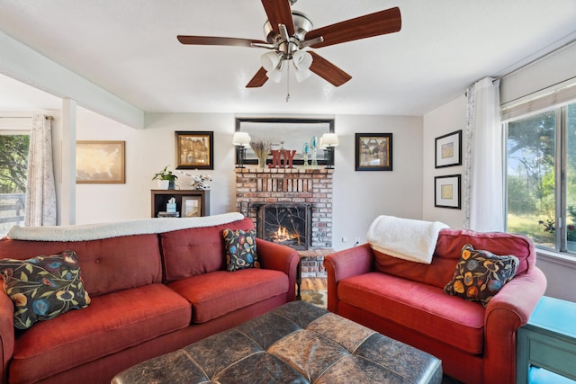 living area with a brick fireplace, ceiling fan, and wood finished floors